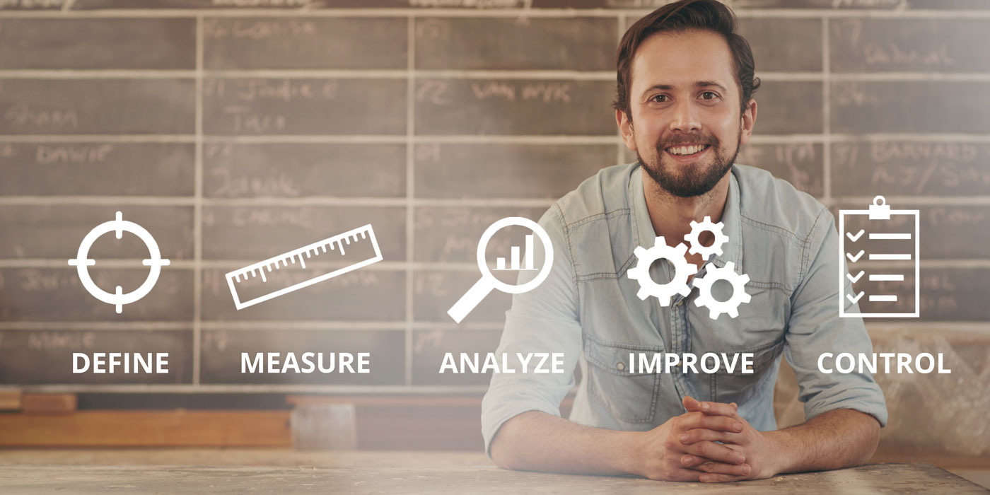 Man sitting at a desk with the Six sigma icons overlaind in the foreground